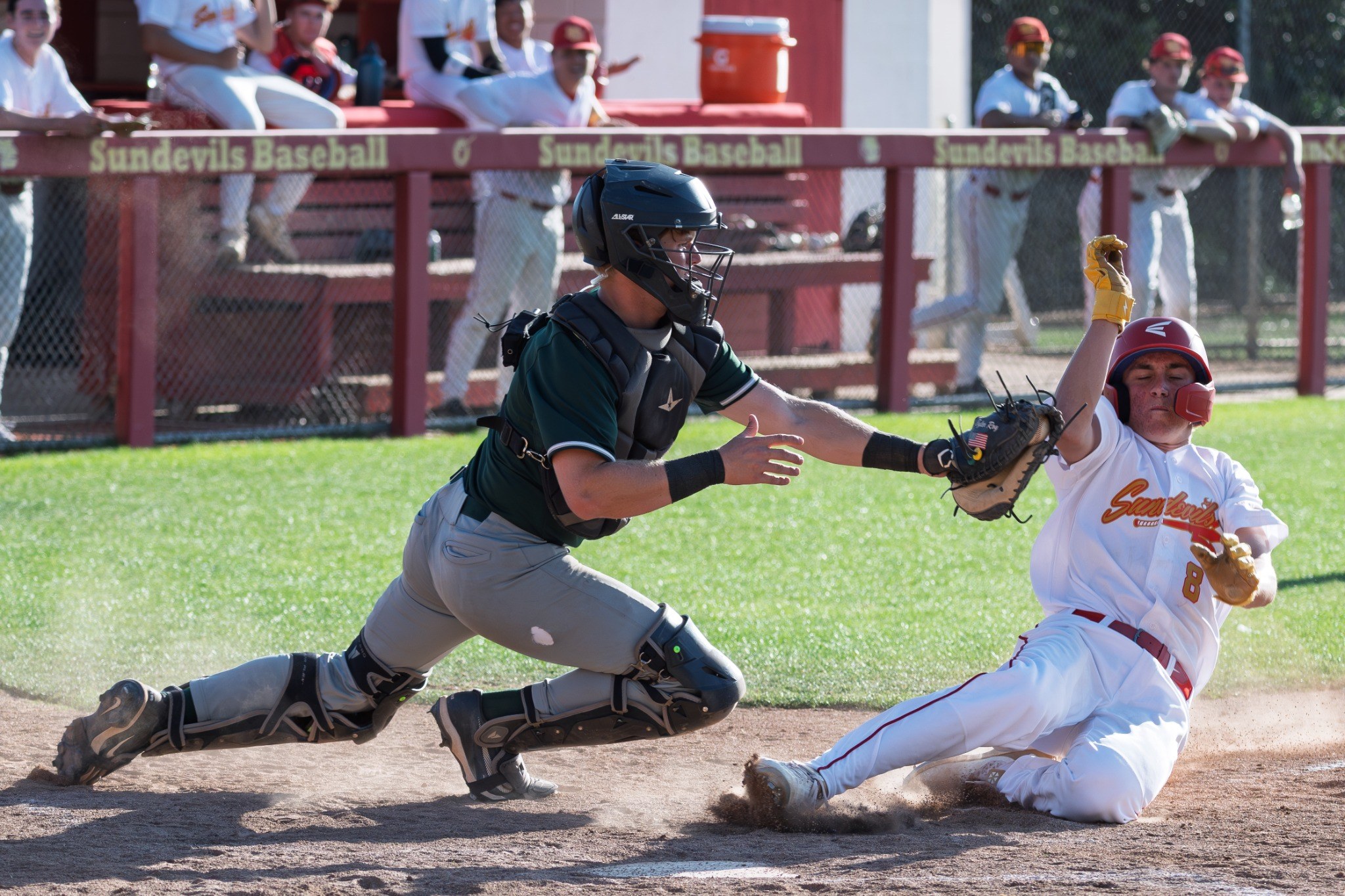 Baseball runner sliding into home plate as catcher reaches for the tag