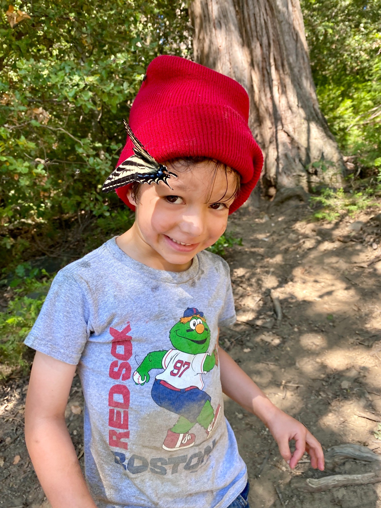 Smiling child outdoors with a butterfly resting near their face